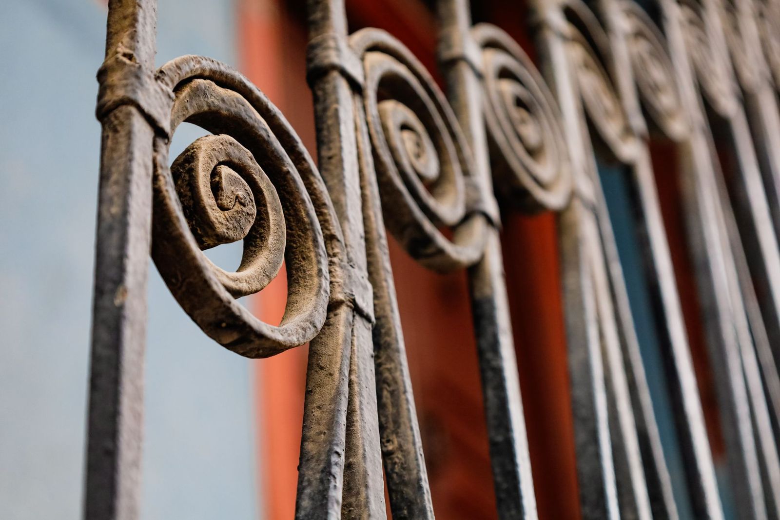 Close-up of decorative dark metal fence pickets ending in spiral scroll details
